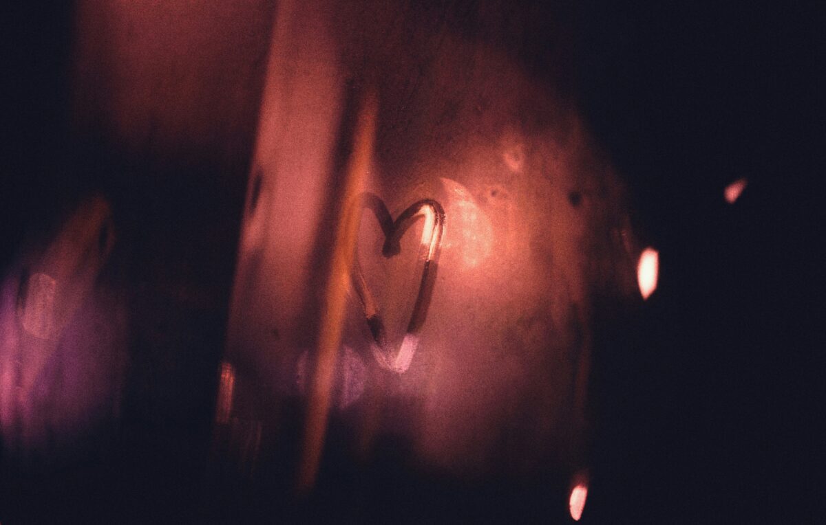 Ikkunalasiin sormella piirretty sydän. Värimaailma on tumman liilan ja vaaleanpunaisen sävyjä